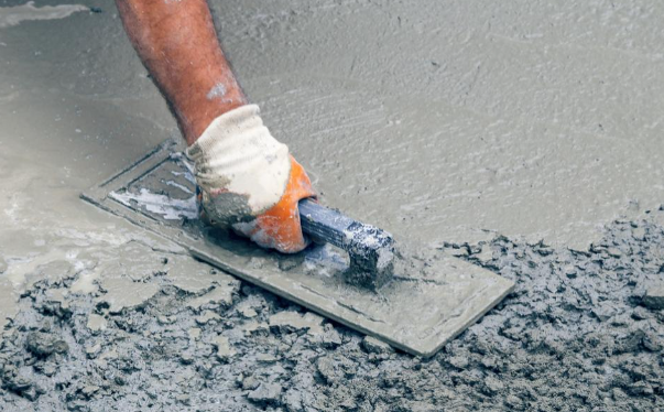 Image showing a professional smoothing freshly poured concrete on a driveway with precision tools.